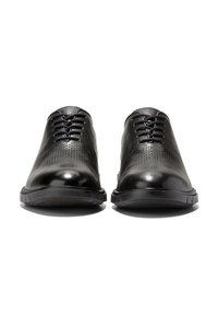Scarpe nere stringate con tomaia in pelle liscia caratterizzata da dettagli perforati, punta arrotondata e suola in gomma texture.