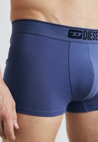 Men's boxer briefs in navy blue, made of smooth fabric. Features a black logo waistband and a fitted design with minimal seams.