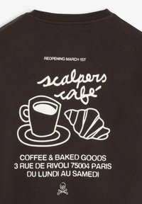 Sort t-shirt med hvidt grafisk motiv af en kaffekop på en tallerken og en croissant, med tekst om en cafés genåbningsdetaljer.