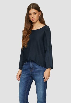 Haut à manches longues bleu marine avec un grand col, coupe ample et poignets côtelés, assorti à un jean en denim bleu au style droit classique.