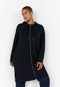 Čierny dlhý hoodie s predným zipsom, bočnými r�ázpormi a kapucňou so sťahovacou šnúrkou. Vyrobený z mäkkého materiálu s voľným strihom, ktorý poskytuje pohodlné pokrytie.