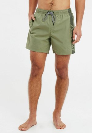 Olijfgroene zwemboxers met een elastische tailleband en trekkoord. Voorzien van zijzakken en een zwart verticale logo-opdruk op het linkerpijpen.