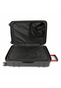 Černý tvrdý kufr s vnitřní síťovanou kapsou, červenými koly a teleskopickou rukojetí, s prostorným, strukturovaným černým podšívkou.