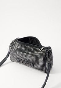 Black fabric handbag with silver studs covering the exterior, rectangular shape, zip closure, and a black shoulder strap. Notable logo detail.