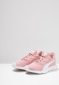 Różowe siatkowe buty sportowe z białymi akcentami, okrągłym noskiem, teksturowaną powierzchnią, płaskimi sznurówkami i amortyzowaną podeszwą, zaprojektowane z myślą o komforcie i wsparciu.