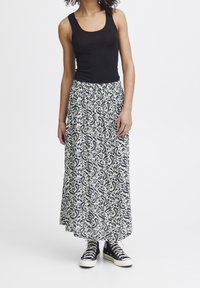 Svart linne och mönstrad maxikjol med krämfärgad botten och marinblå virvlar. Kombinerad med svarta högtoppsneakers med vita sulor.