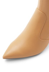 Stivaletto in pelle beige con punta a punta, caratterizzato da una texture liscia e senza hardware visibile, che evidenzia un design elegante e moderno.