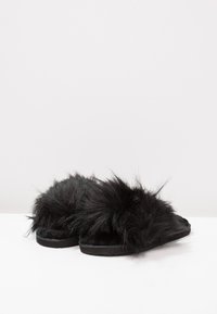Black fur slip-on slippers with a textured, fluffy upper and a flat black sole, featuring a soft interior lining for comfort.