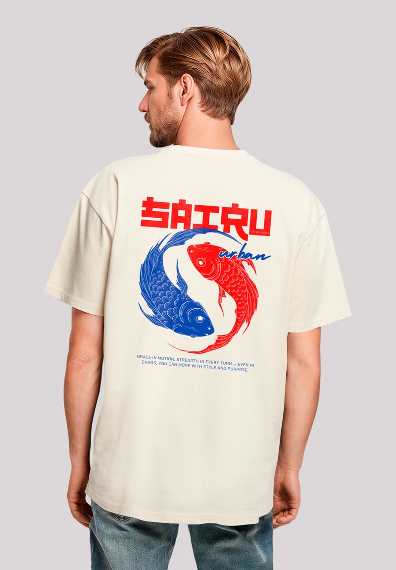 Beige oversized t-shirt featuring a red and blue koi fish graphic, bold red text, and a smooth cotton texture.