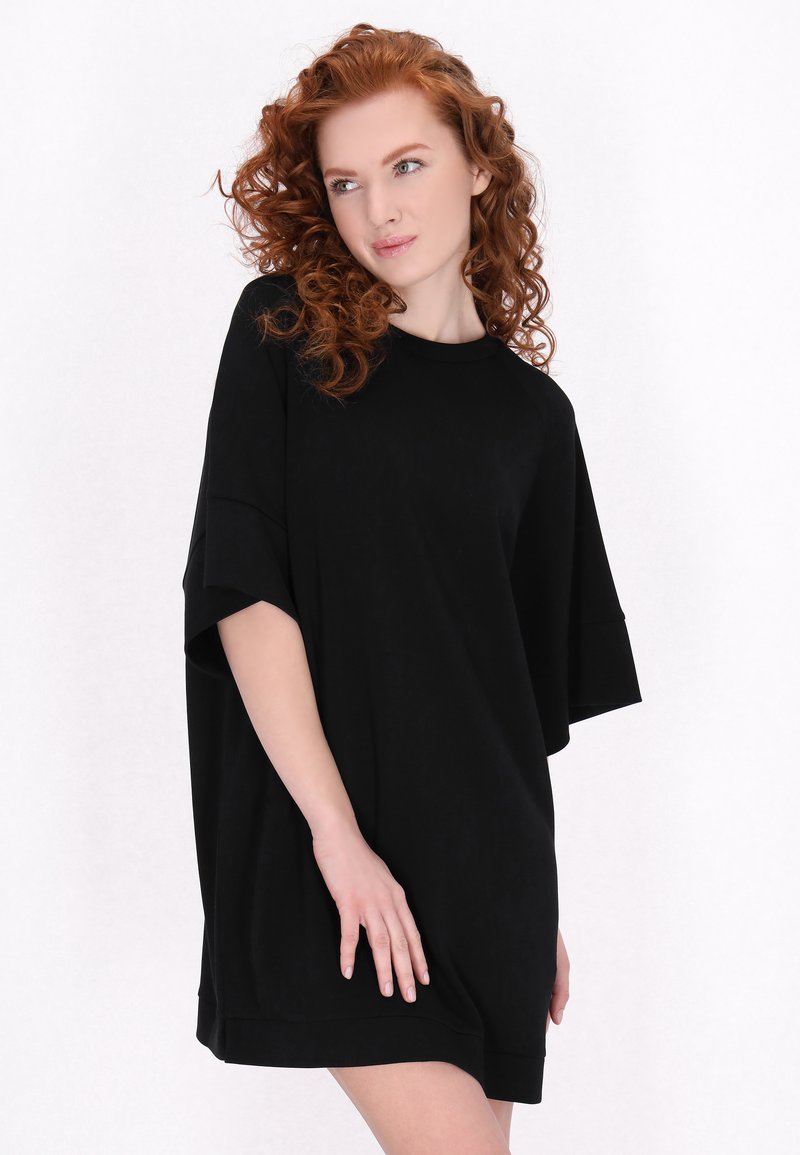 Rochie neagră din bumbac, oversized, cu mâneci scurte, realizată dintr-un material moale. Prezintă un guler rotund clasic și o croială lejeră.