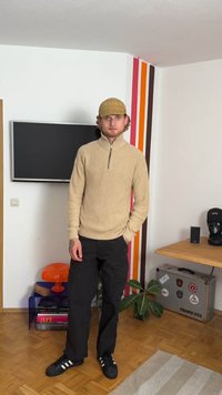 Beige ribbed knit pullover with a high collar and half zipper, paired with black cargo pants and black sneakers with white stripes.