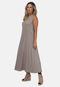 Sukienka bez rękawów, do kolan, w jasnobeżowym materiale o luźnym kroju. Posiada dekolt w serek i dekoracyjne guziki z przodu.