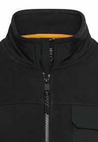 Schwarze Fleecejacke mit hohem Kragen, gelber Innenfütterung, Frontreißverschluss und einer Brusttasche. Aus strukturiertem Stoff gefertigt.