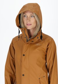 Giacca impermeabile marrone con cappuccio, dotata di zip frontale, bottoni neri e tasca laterale. Tessuto liscio, progettata per l'abbigliamento outdoor.