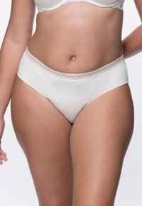 Svetlo bež ženske spodnjice z gladko teksturo, ki imajo nizek kroj in subtilno kontrastno šivanje na pasu.