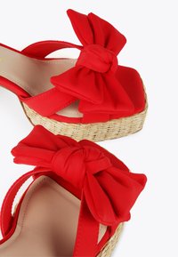 Crvene platforme sandale s širokim tkanim mašnama na trakama, pletene bež espadrile stil đonovi i glatka unutrašnjost.