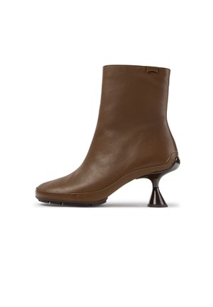 Stivaletto in pelle marrone con tacco corto, svasato e scolpito e punta rotonda, con una piccola etichetta logo vicino al bordo superiore.