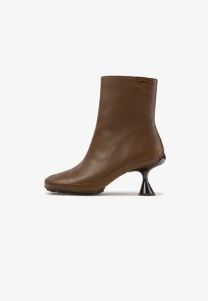Stivaletto in pelle marrone con tacco corto, svasato e scolpito e punta rotonda, con una piccola etichetta logo vicino al bordo superiore.