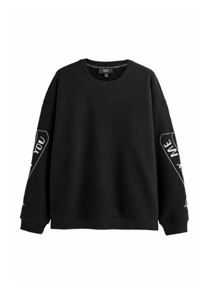 Zwarte lange mouw crewneck sweat met witte tekstontwerpen op beide mouwen, geribde manchetten en zoom, afgebeeld op een witte achtergrond.