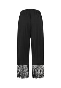 Pantalon noir à jambes larges avec ceinture élastique et bordure en dentelle florale en bas de chaque jambe.