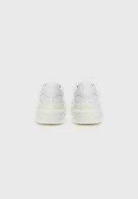 Baskets blanches avec une tige en simili cuir lisse, un col rembourré et une semelle en caoutchouc épaisse ; design minimaliste sans marque visible.