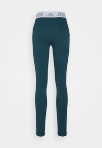 Teall leggingsit, jotka on muotoiltu tiukasti ja valmistettu joustavasta kankaasta. Niissä on leveä, teksturoitu valkoinen vyötärö vyö, jossa on "ADIDAS"-logo.