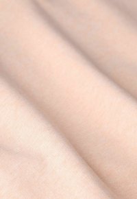 Tissu rose clair avec une texture lisse, présentant un léger étirement et une finition douce. Le matériau présente de doux plis et des rides.