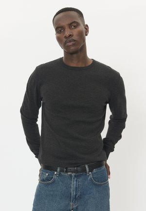 Dunkelgrauer, langärmeliger Pullover mit Rundhalsausschnitt, aus einem strukturierten Stoff, kombiniert mit blauen Denim-Jeans und einem schwarzen Gürtel.