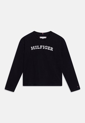 Schwarzes Langarmshirt mit Rundhalsausschnitt und dem Schriftzug „HILFIGER“ in weißen Großbuchstaben quer über der Brust sowie kleinem Logo am linken Ärmelbündchen.