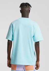 Light blue cotton t-shirt with short sleeves, crew neck, and a relaxed fit. Smooth texture, no visible patterns or accents.