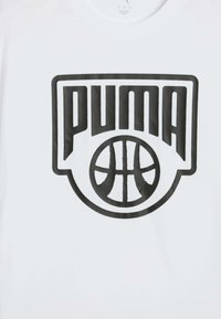 Texto negro "PUMA" sobre un contorno de baloncesto, impreso en un fondo de tela blanca.