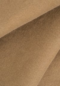 Primer plano de tela de pana beige doblada que muestra su patrón estriado y texturizado.