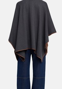 Szary poncho z brązowym wykończeniem, wykonane z miękkiego materiału. Posiada luźny kształt, który opada na ramiona i plecy.