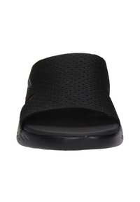 Zwarte schuifslipper met een textielband, een open teenontwerp en een vlakke rubberen zool. Heeft een lichte glans op het oppervlak van de band.