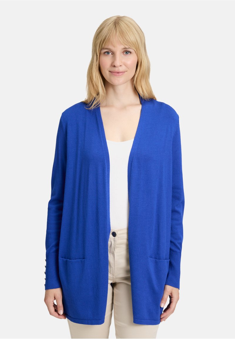 Cardigan blu aperto davanti in materiale a maglia morbida con maniche lunghe, due tasche frontali e polsini a coste. Texture liscia e design leggero.