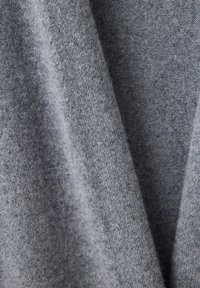 Tissu gris doux avec une texture fine et légèrement duveteuse suspendu en plis délicats.