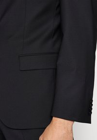 Zwarte colbertdetails, met een gladde textuur, een getailleerde pasvorm, een enkele borstzak en drie knopen bij de manchetten.