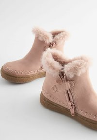 Roze enkellaarzen met een bontafwerking bij de kraag, gemaakt van zacht suede-achtig materiaal, met een zijrits en een gestructureerde rubberen zool.