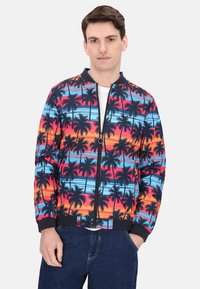 Kleurige bomberjack met een tropisch palmboomprint, voorzien van levendige blauwe, oranje en roze tinten op een zwarte achtergrond. Met ritssluiting aan de voorkant.