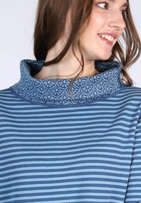 Topp mit Schalkragen in blau gestreiftem Muster und dekorativem blauen Blumendesign am Kragen. Aus weichem Stoff gefertigt, präsentiert sich in einem lässigen Schnitt.