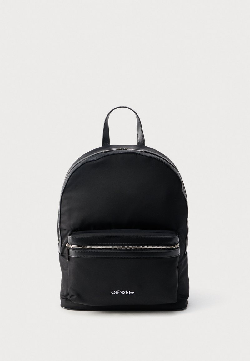 Sac à dos noir Off-White avec poche avant zippée, tirettes de fermeture éclair en cuir et poignée supérieure sur fond gris neutre.