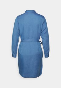 Vestido de ganga com gola, mangas longas, faixa na cintura e comprimento a meio do coxa. Apresenta uma cor azul clara e uma textura suave.