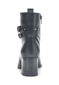 Bottes noires en cuir jusqu'à la cheville avec un talon carré, des sangles décoratives et des clous en métal. Texture lisse avec une fermeture éclair à l'arrière.