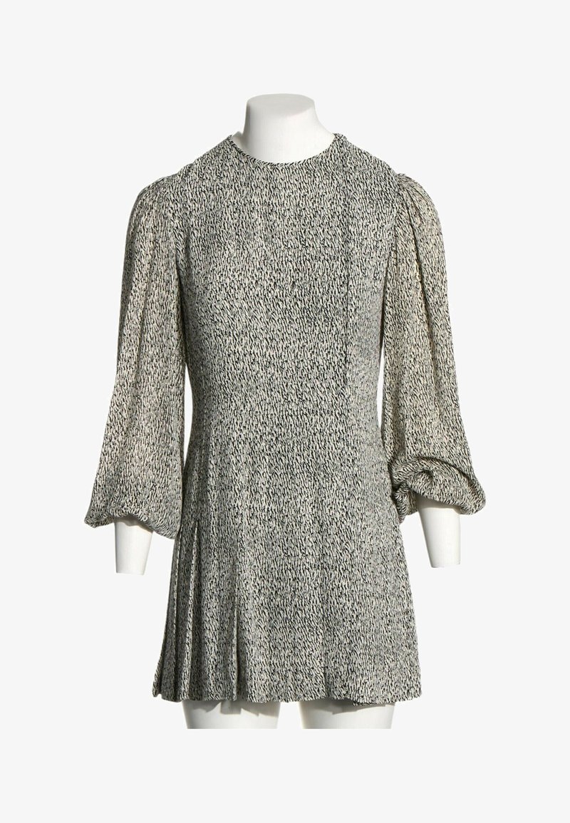 Robe grise à manches longues avec un motif tacheté noir, encolure ronde et manches volumineuses froncées aux poignets sur un mannequin sans tête.