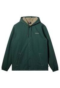 Veste à capuche verte avec une doublure en polaire beige douce, boutons-pression, poignets élastiques, deux poches latérales et accents de couture blanche.