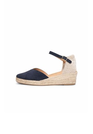 Zapato espadrille de cuña con puntera cerrada azul marino, parte trasera beige tejida, correa en el tobillo con hebilla y suela trenzada de yute.