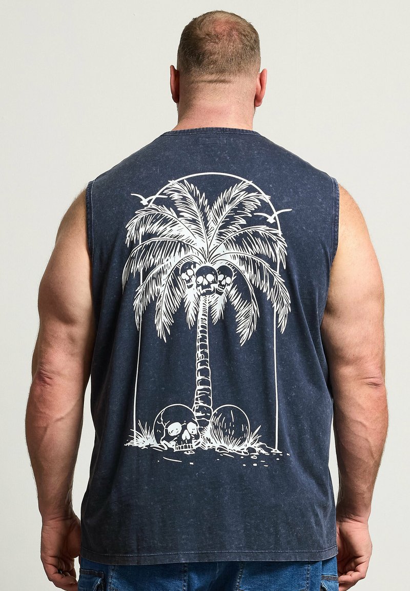 Homme vu de dos portant un t-shirt sans manches bleu marine avec un motif blanc représentant un palmier et des crânes dans le dos.