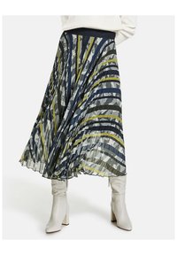 Sisältää tummansinisen, vihreän ja harmaan raidallisen kuosin pliseerattu midihame. Teksturoidusta kankaasta valmistettu kevyt hame yhdistetty istuviin valkoisiin saappaisiin.