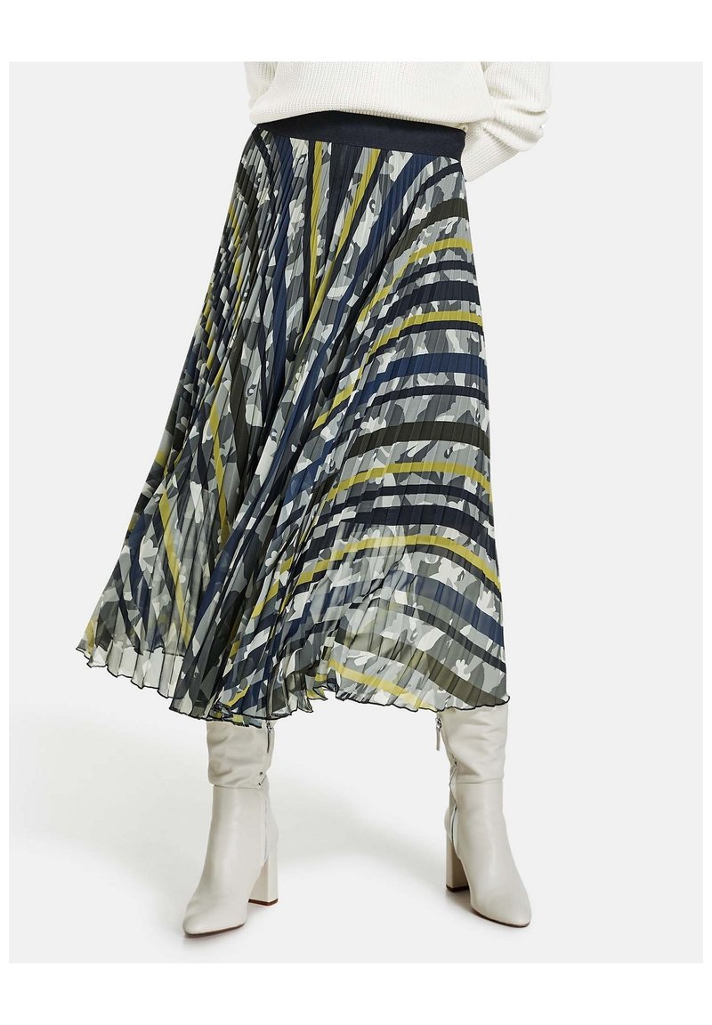 Sisältää tummansinisen, vihreän ja harmaan raidallisen kuosin pliseerattu midihame. Teksturoidusta kankaasta valmistettu kevyt hame yhdistetty istuviin valkoisiin saappaisiin.