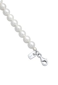 Hvid perlearmbånd med en sølvfarvet klipslås. Har runde, glatte perler og et lille mærke nær låsen.